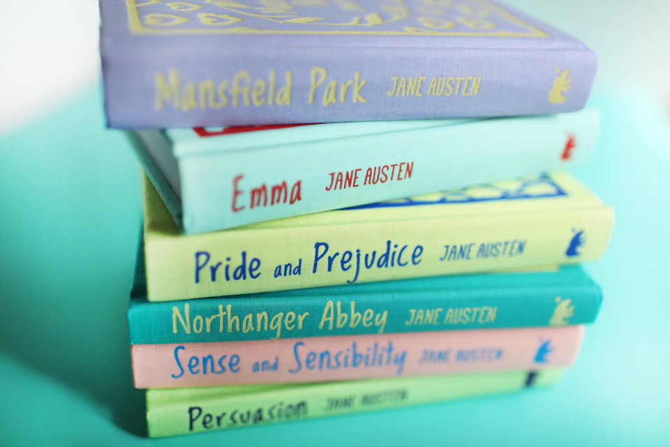 Stack of six Jane Austen books, including "Mansfield Park," "Emma," "Pride and Prejudice," "Northanger Abbey," "Sense and Sensibility," and "Persuasion."