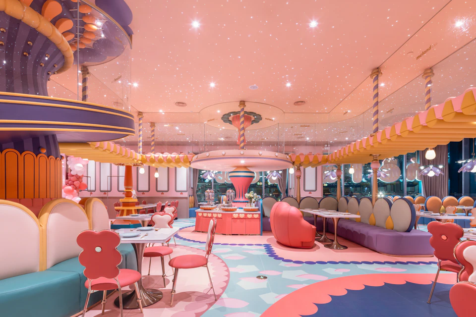 A colorful, whimsical interior with pink and pastel decor, featuring playful furniture and a candy-themed design.