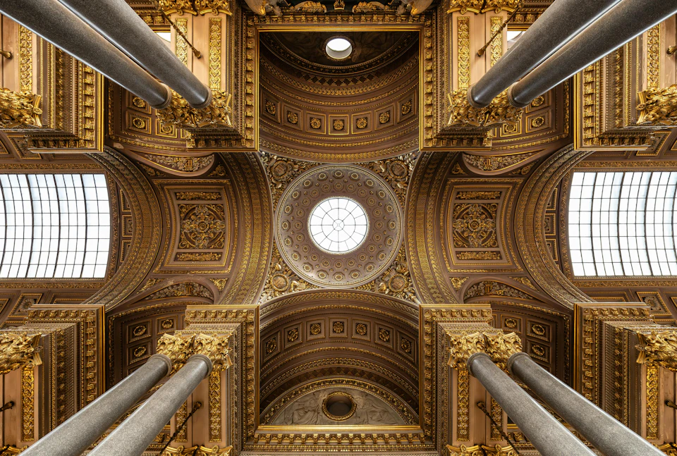Elaborate, gold-ornamented dome ceiling viewed from below, with large columns and detailed carvings.