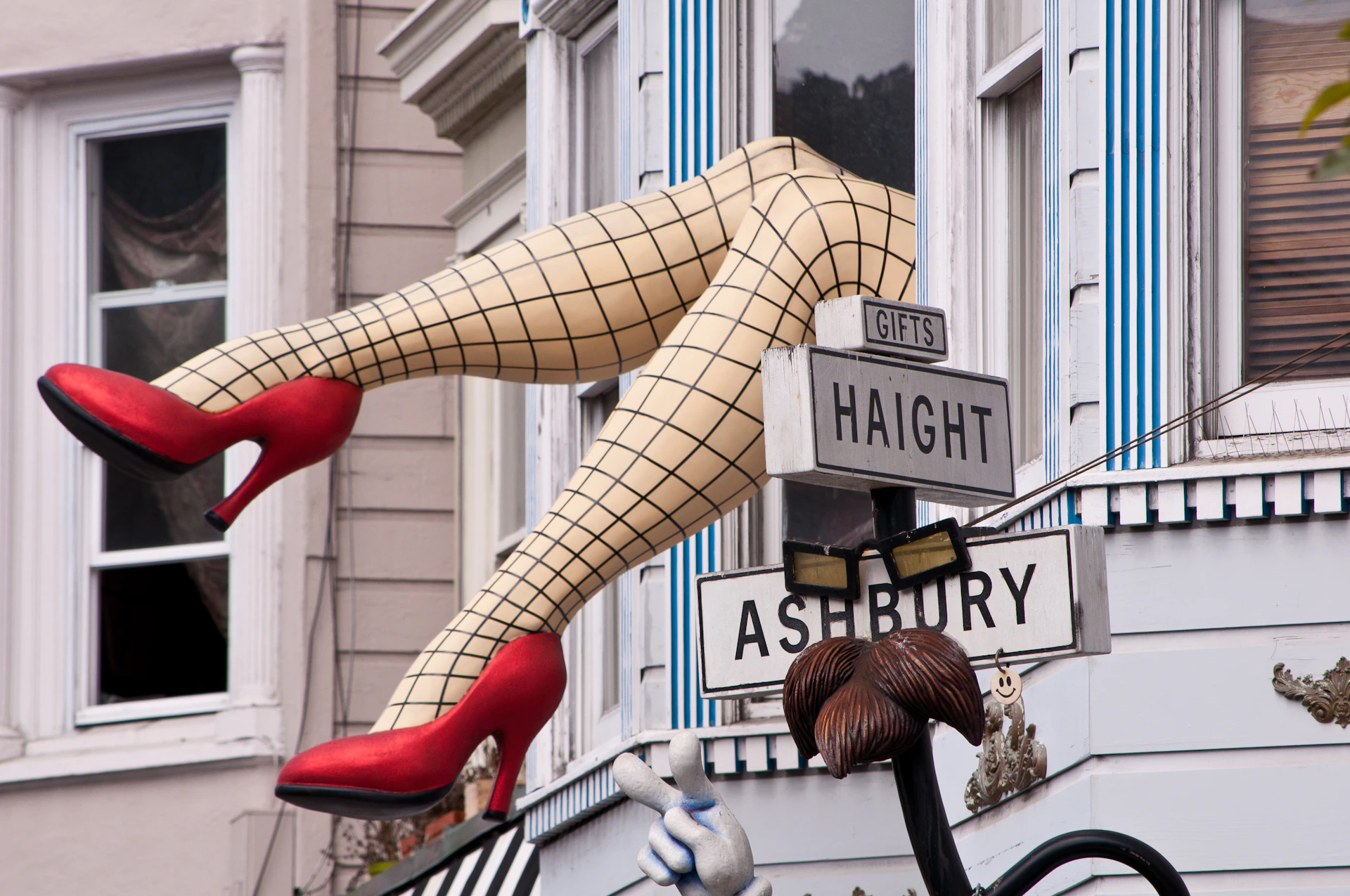 A mannequin's legs, in fishnet stockings and red heels, protrude from a window above Haight and Ashbury street signs.