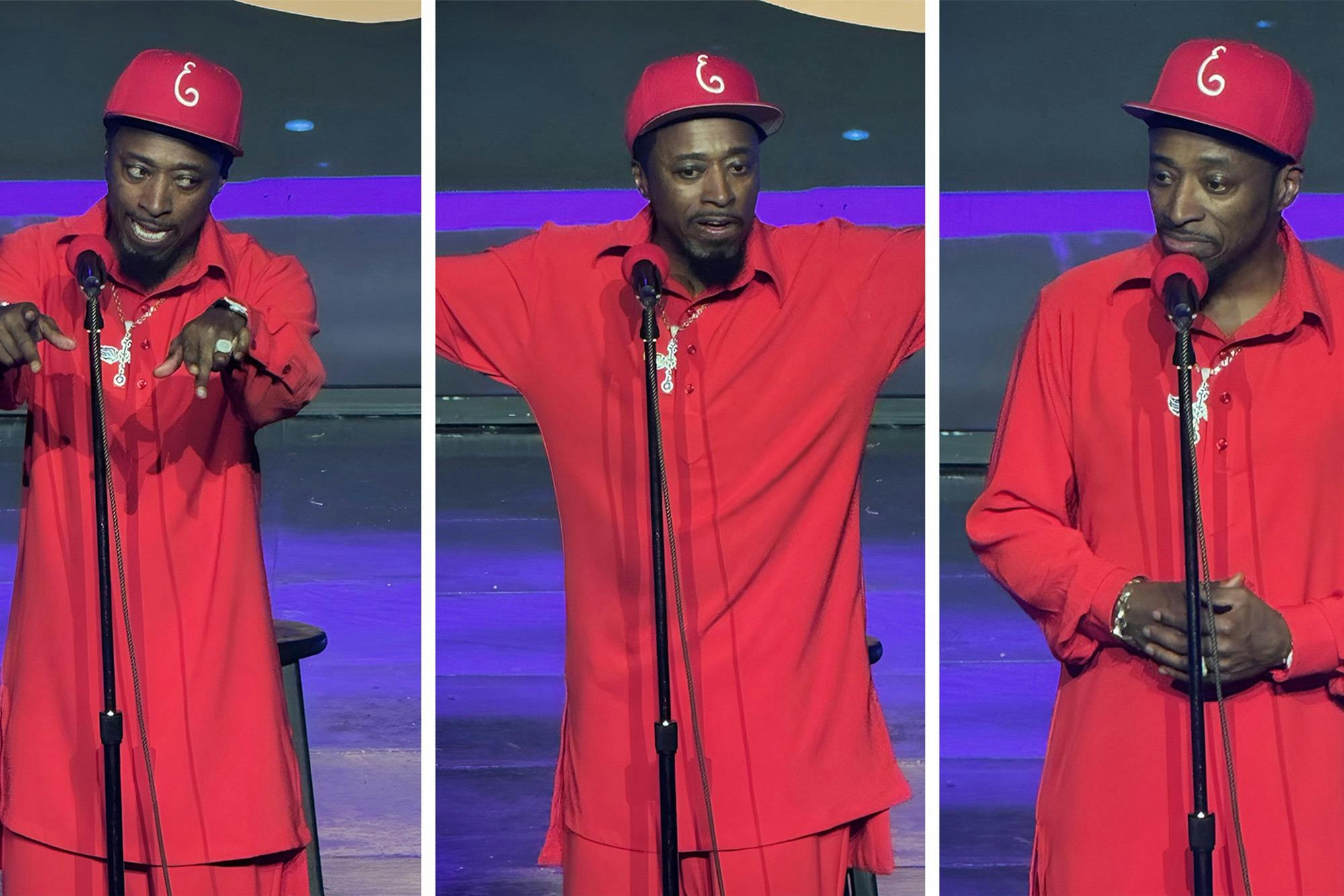 A person in a red outfit and cap performing on stage with a microphone stand in front of them.