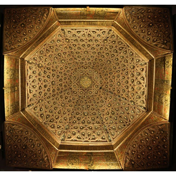Intricate, geometric pattern on an ornate, octagonal ceiling with gold and earthy tones.