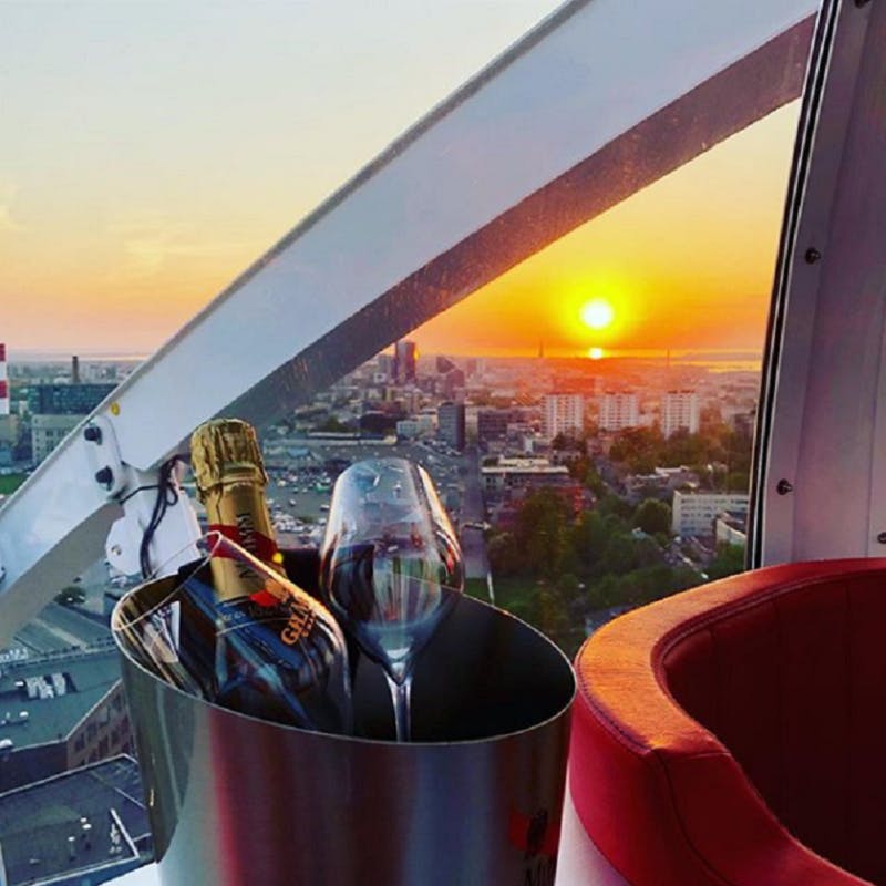 A bucket with champagne and glasses in front of a window showing a cityscape at sunset.