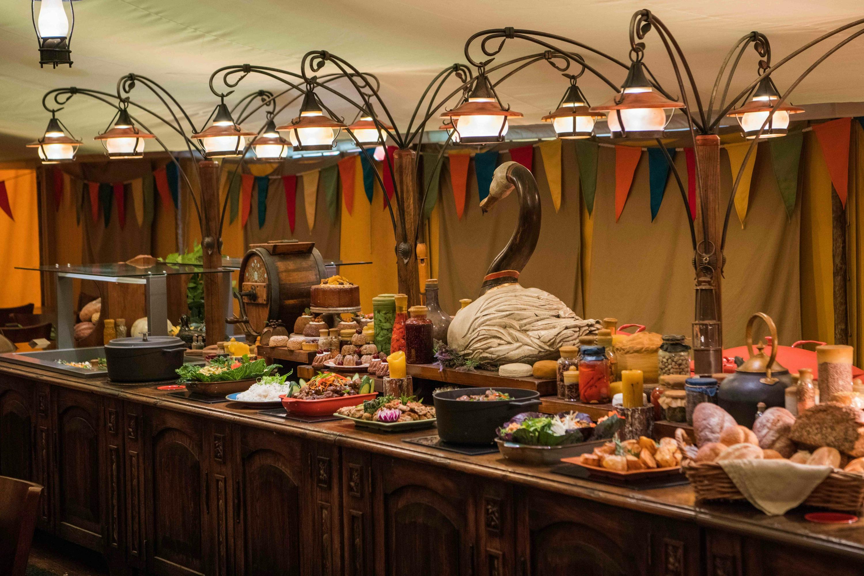 A buffet table with various dishes and decorations, including a swan sculpture and colorful bunting in the background.