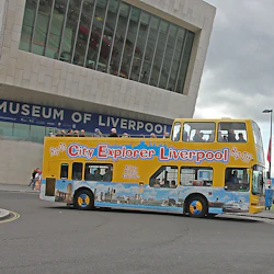 Dubbeldäckare med turnébuss märkt "City Explorer Liverpool" nära Museum of Liverpool på en molnig dag.