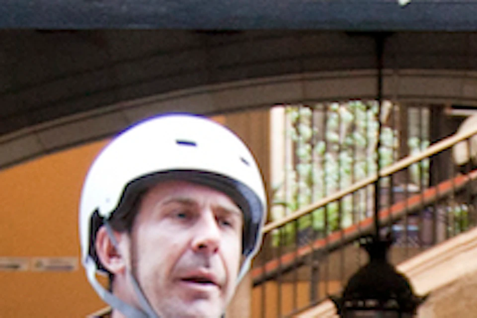 Three people wearing helmets ride Segways in an archway with stone walls and a gated passage in the background.