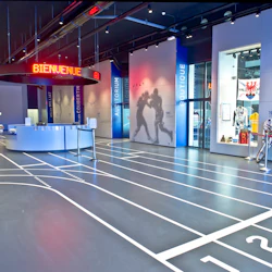 Museumsentré med en färgglad clownbil, racerbanelinjer på golvet, välkomstskylt och utställningar som visar atletiska minnessaker.