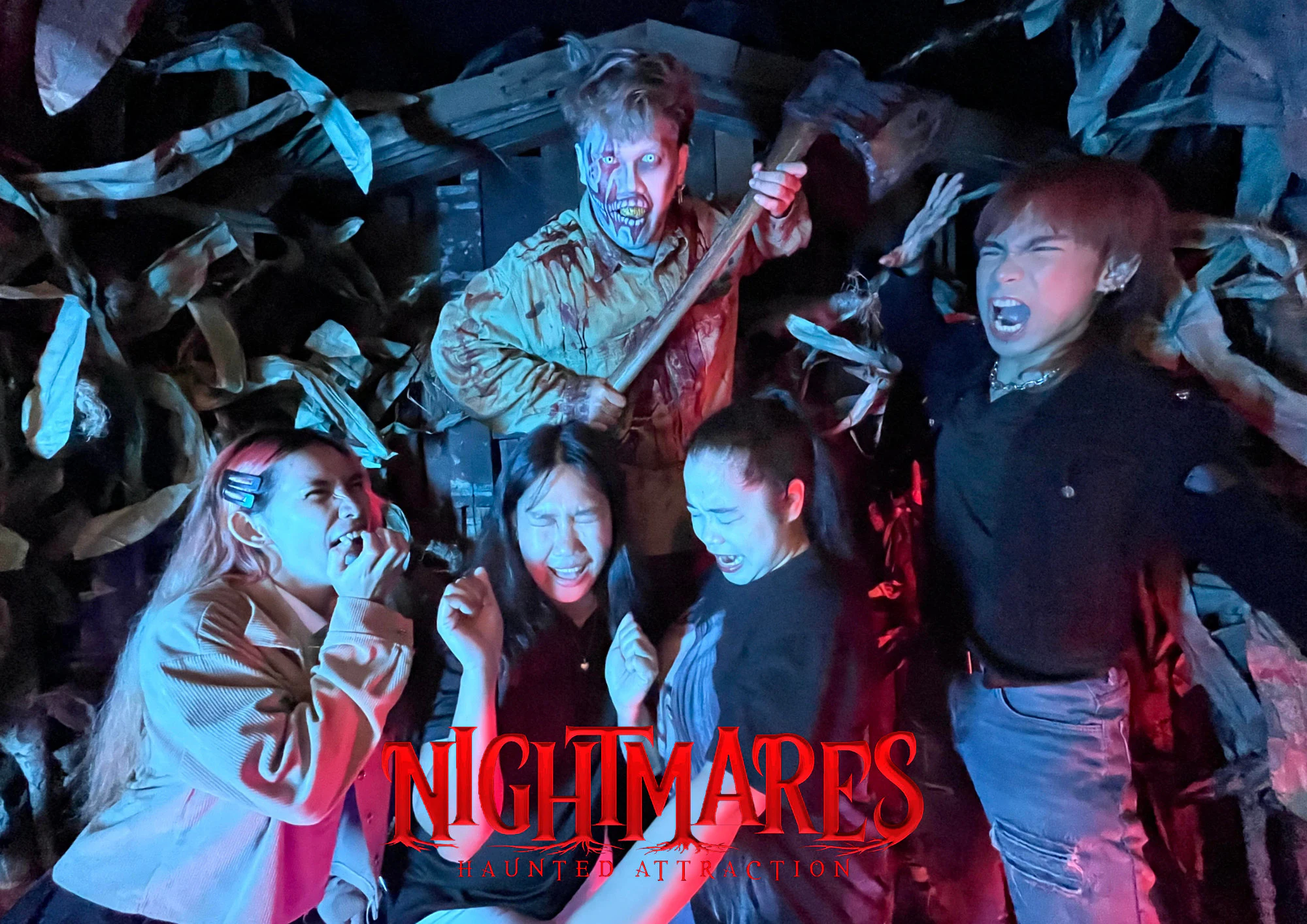 A group of people in a horror-themed setting, one in costume holding an axe, others reacting with fearful expressions.