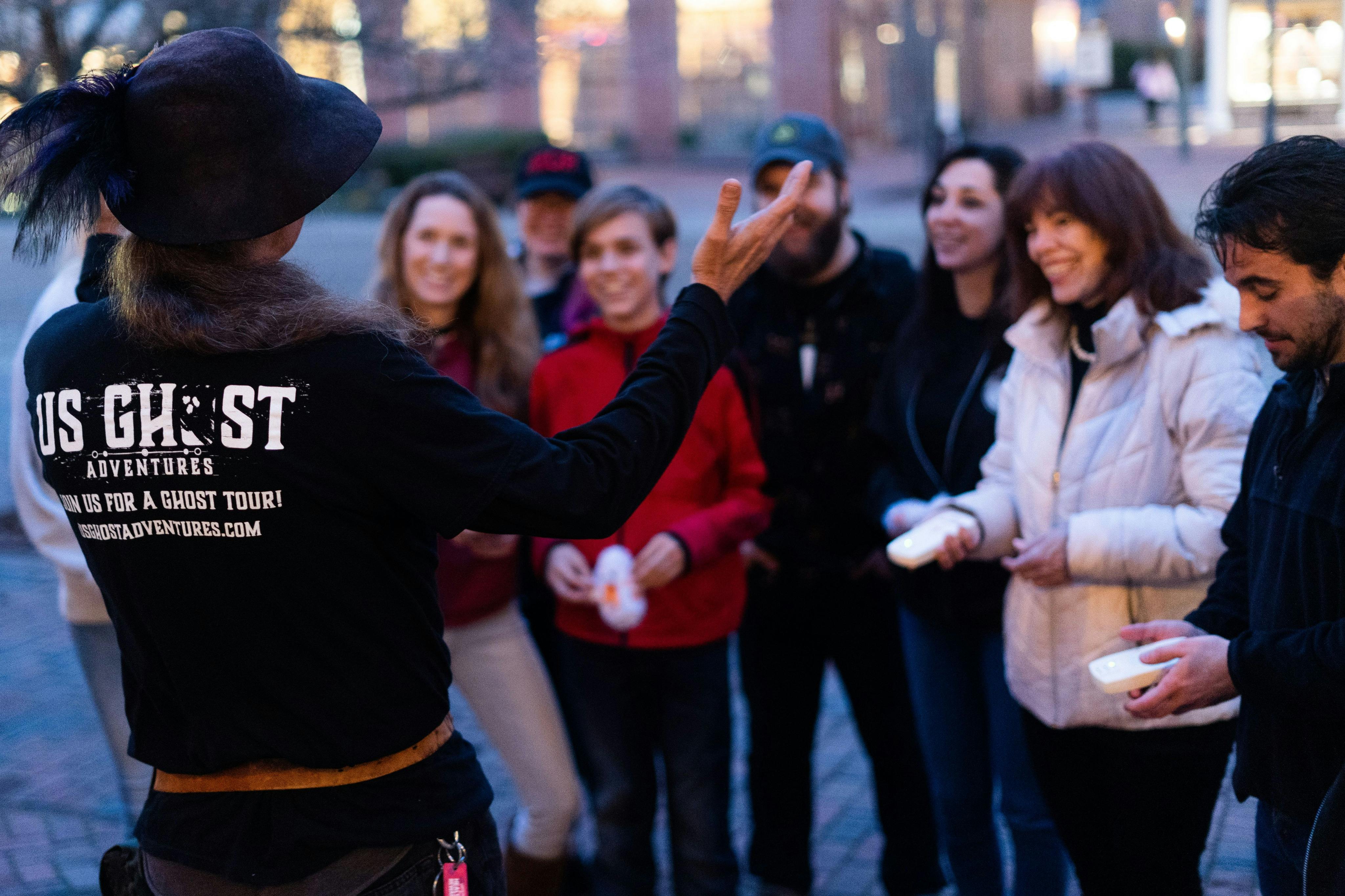 Tour guide making a tour group laugh while they hold EMF detectors, picking up on spiritual activity