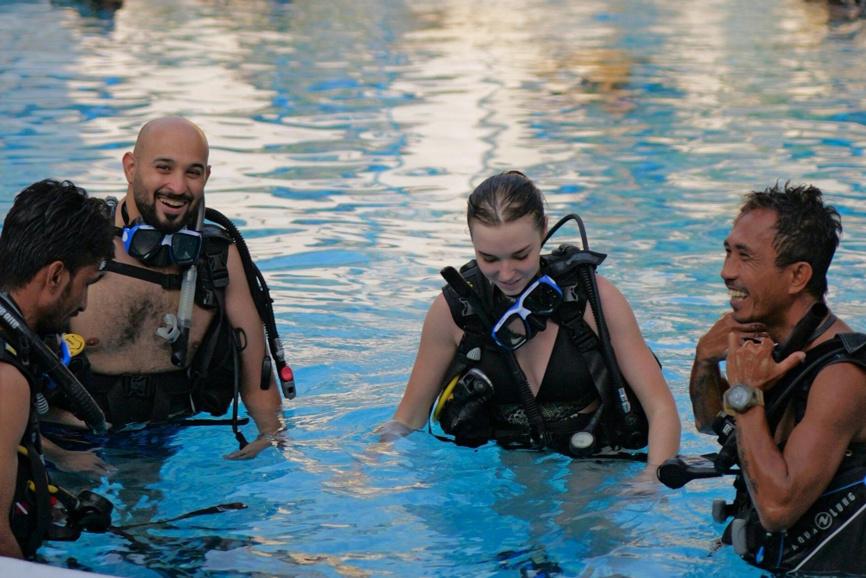 スキューバダイビング用品を着た3人がスイミングプールに立ち、微笑んでダイビングの準備をしています。
