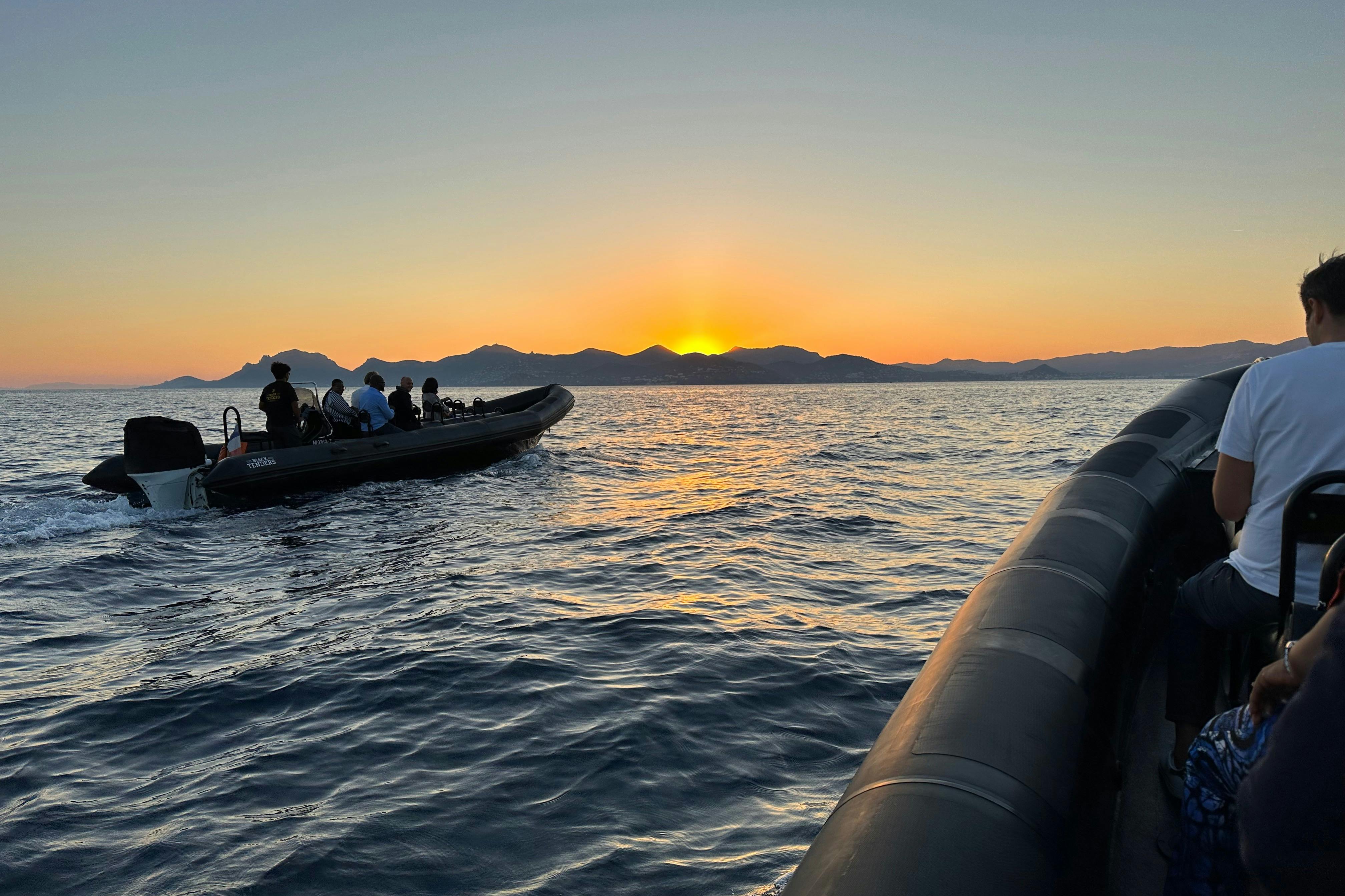 Two boats on a calm sea at sunset with distant mountains on the horizon.
