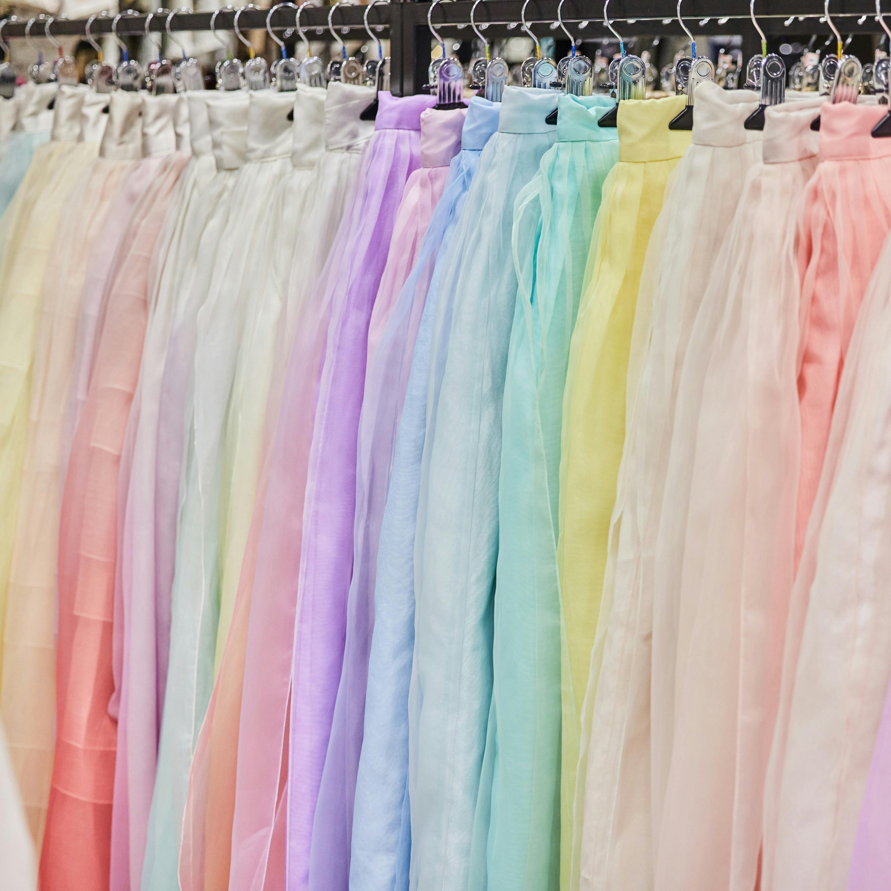 A rack of pastel-colored fabric, including shades of pink, purple, blue, green, and yellow, displayed hanging in a shop.