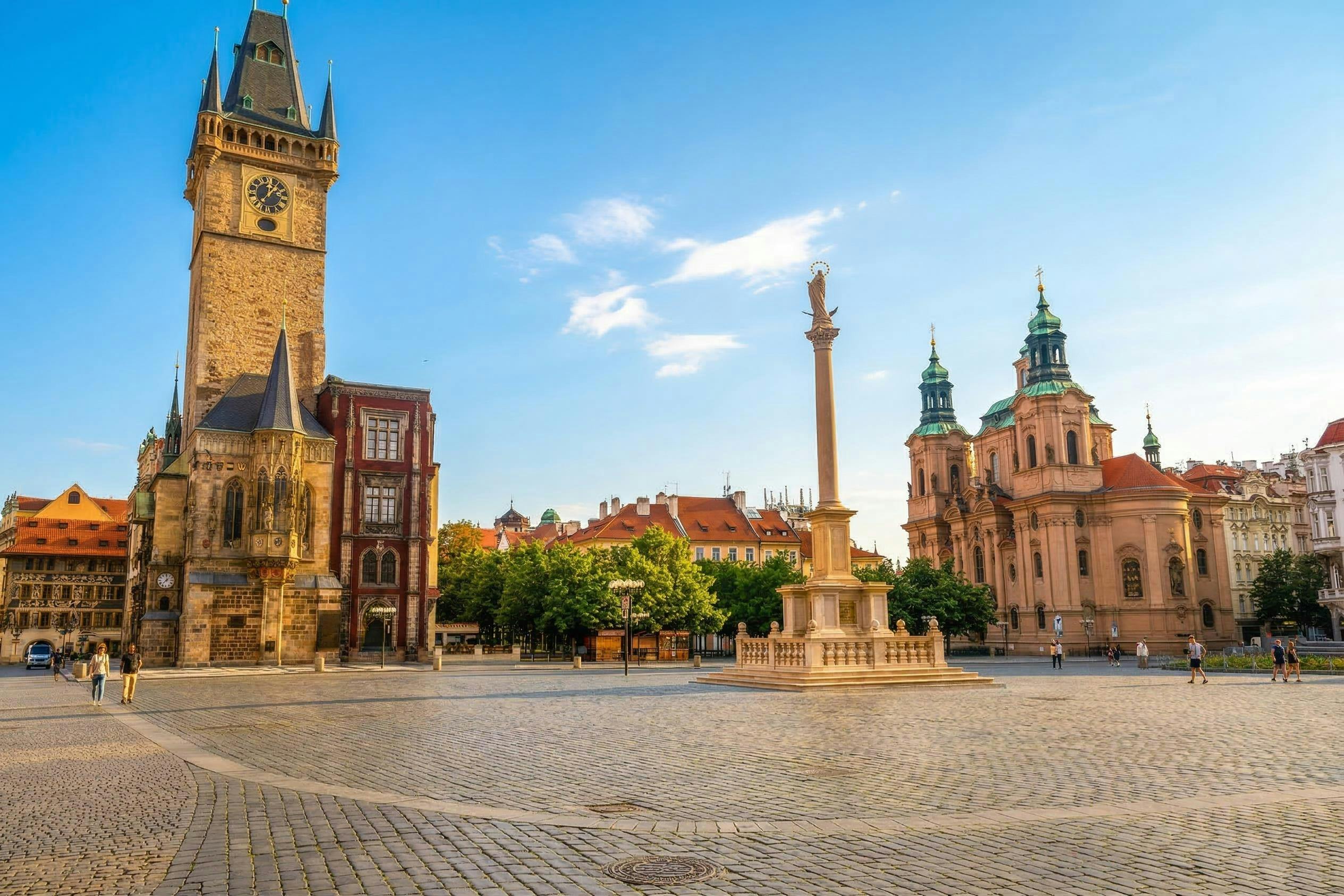 역사적인 건물, 높은 기둥, 맑고 푸른 하늘 아래 나무가 있는 도시 광장.