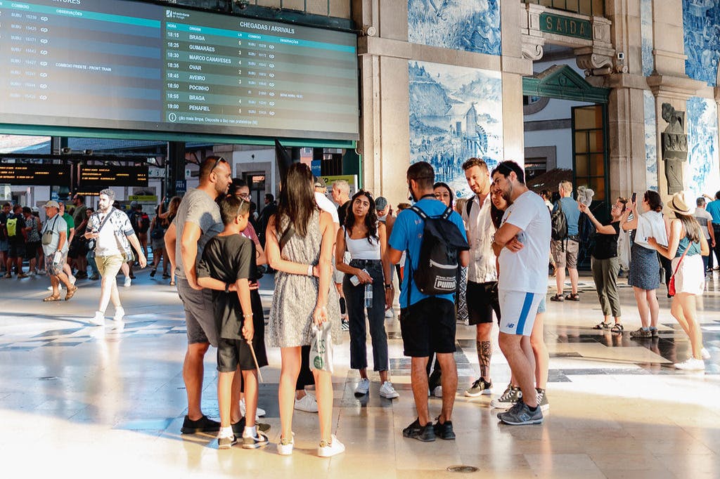 A group and their guide in the hall of a train station surrounded by blue tiles