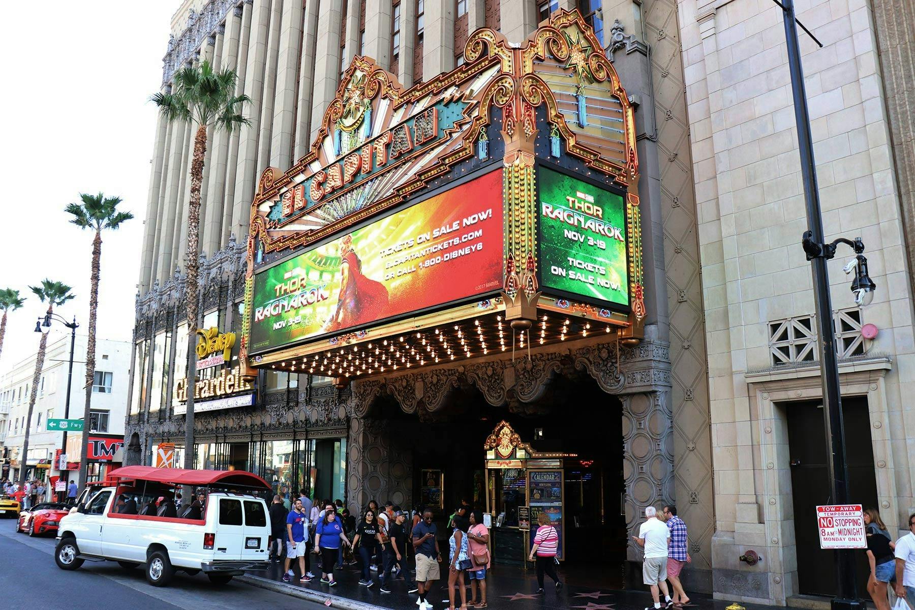 Persones de peu davant de l'entrada ornamentada d'un teatre, amb una marquesina que anuncia la pel·lícula "Thor: Ragnarok".