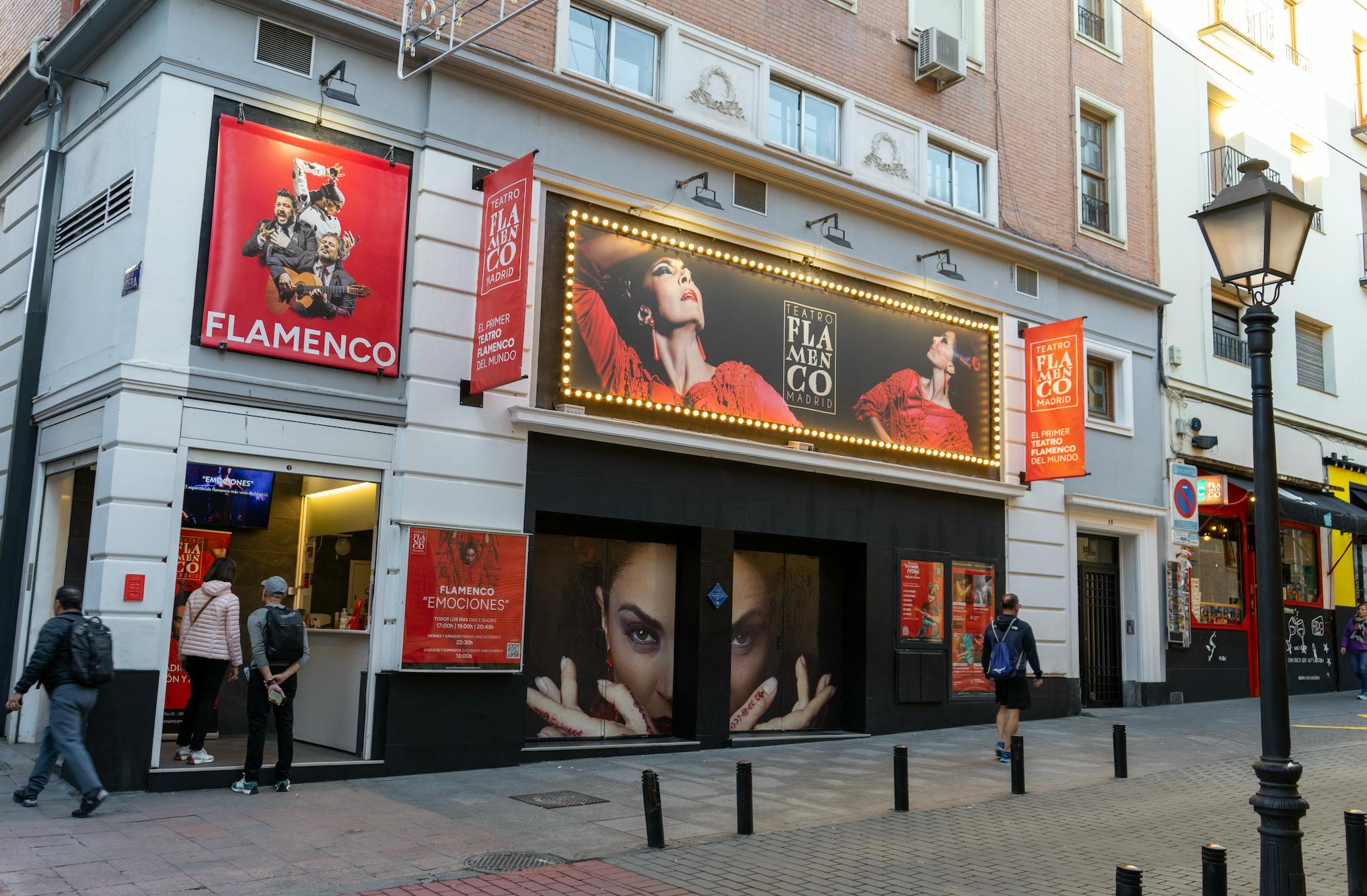 Vstup do divadla s plakáty s flamencovou tématikou a osvětleným stanem s reklamou na představení.