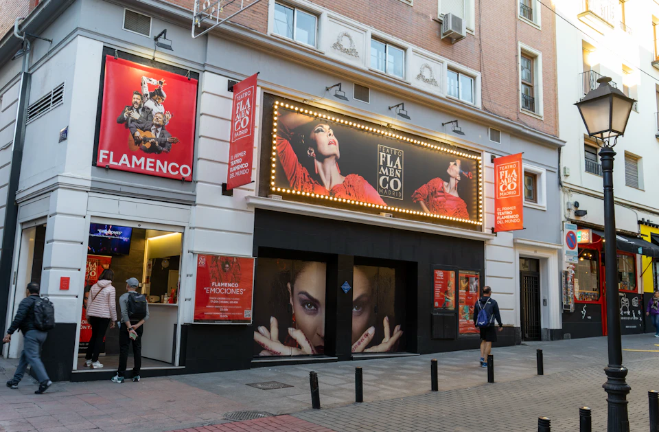 A theatre entrance with flamenco-themed posters and an illuminated marquee displaying an advertisement for a performance.