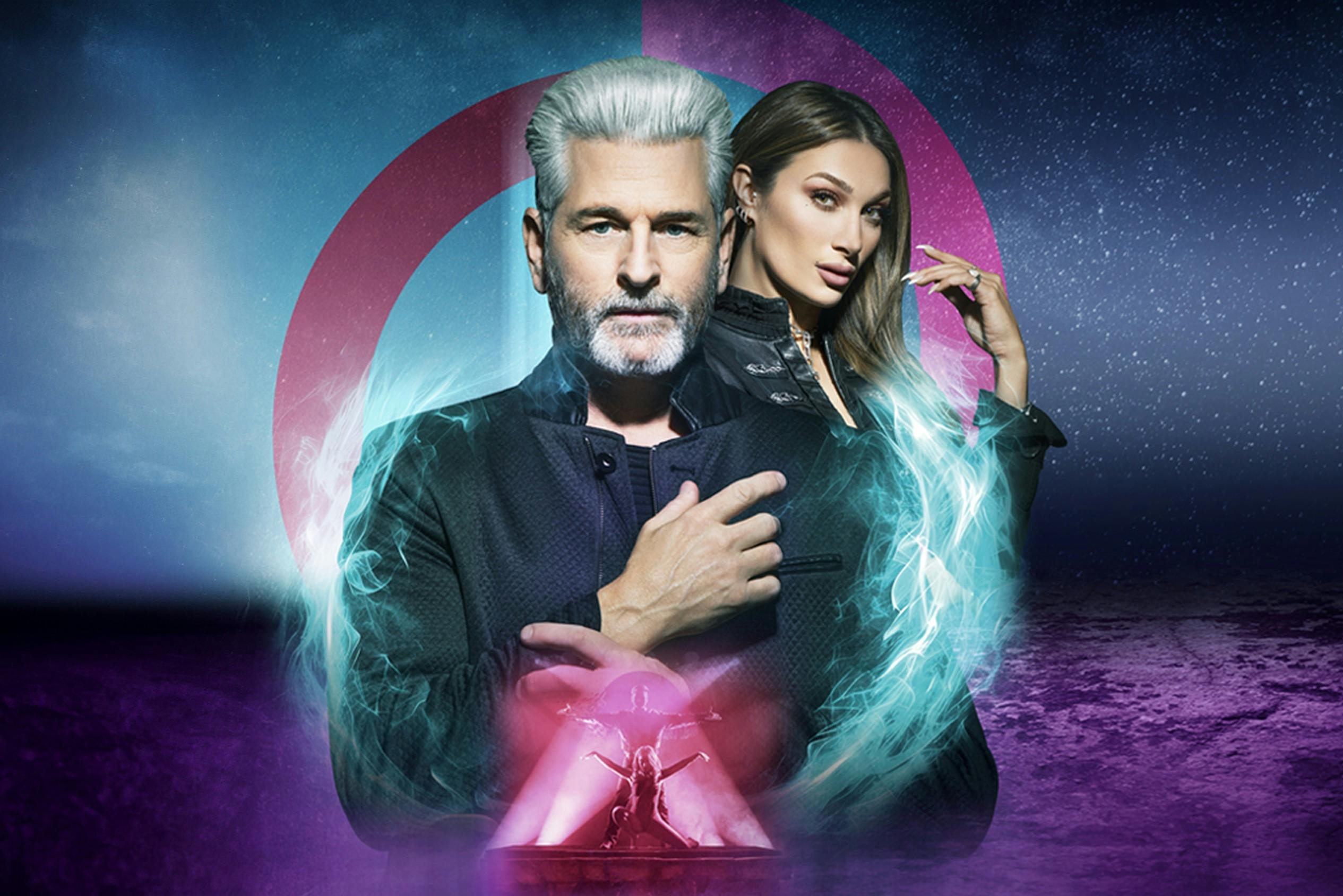 Muž se šedými vlasy a žena s dlouhými vlasy stojí proti kosmickému pozadí se zářící modrou energií kolem nich.