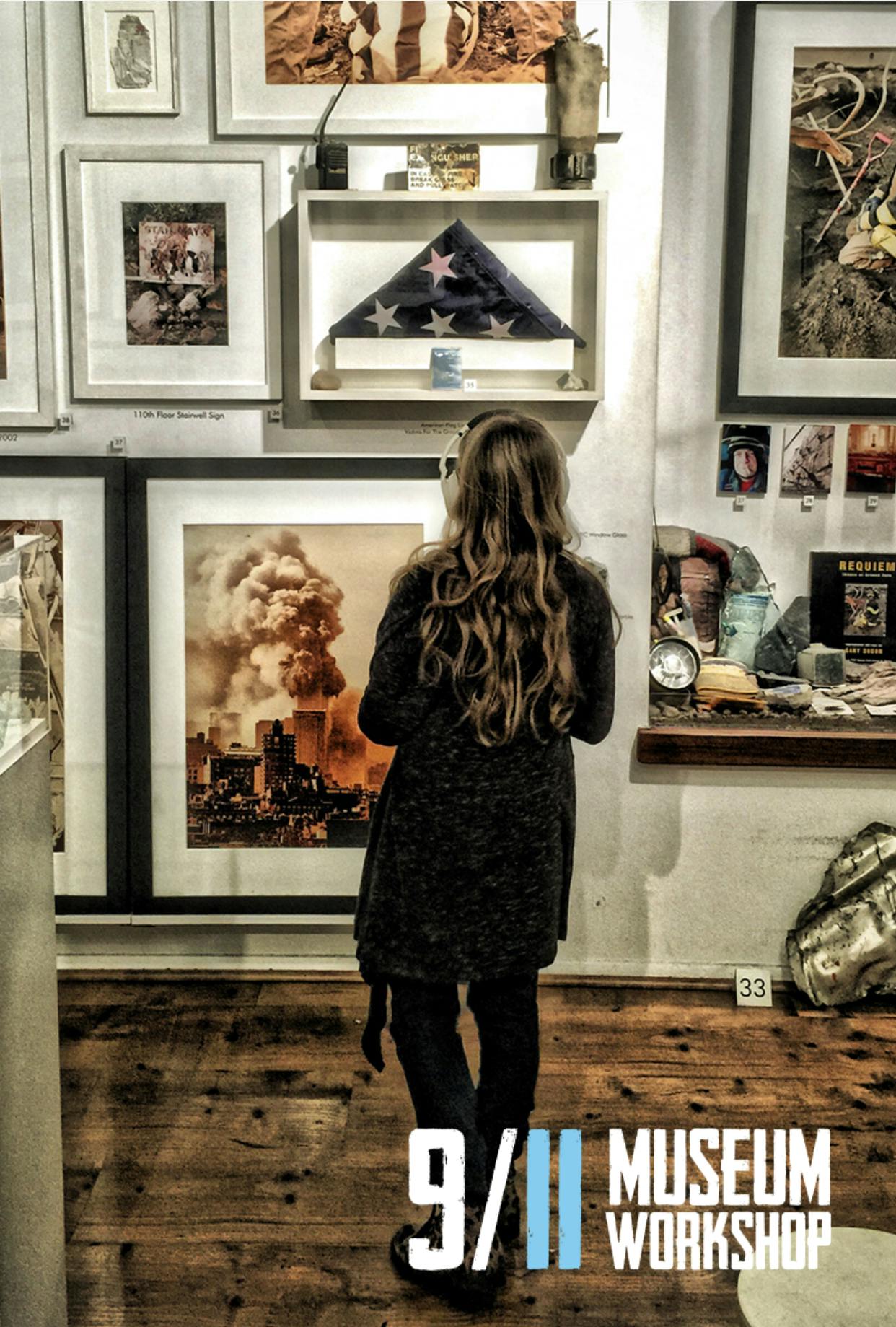 A woman with long hair looks at a 9/11 museum display featuring photos, a folded flag, and various artifacts.