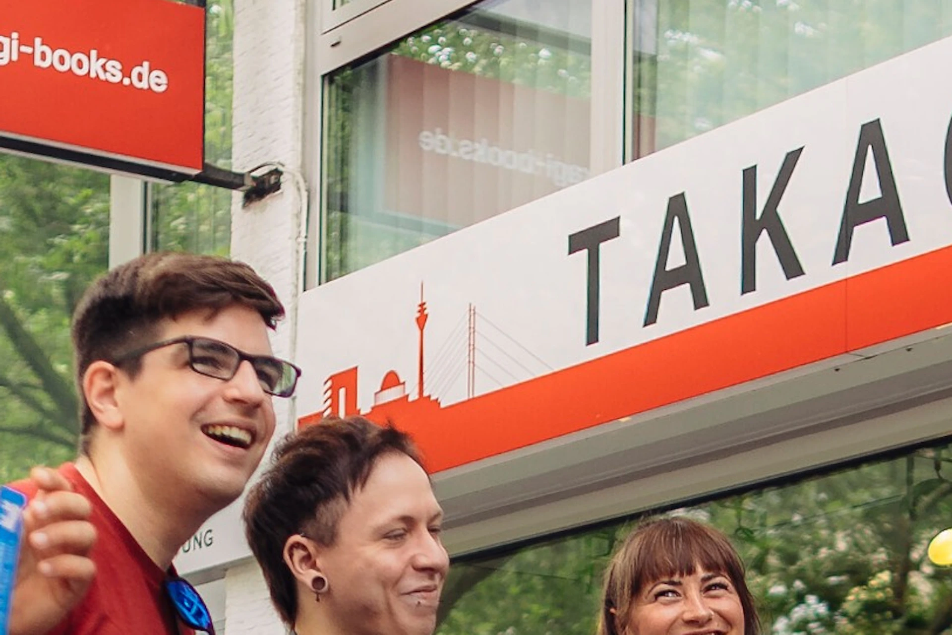 A group of five people standing outside a bookstore named Takagi Books & More on a city street.