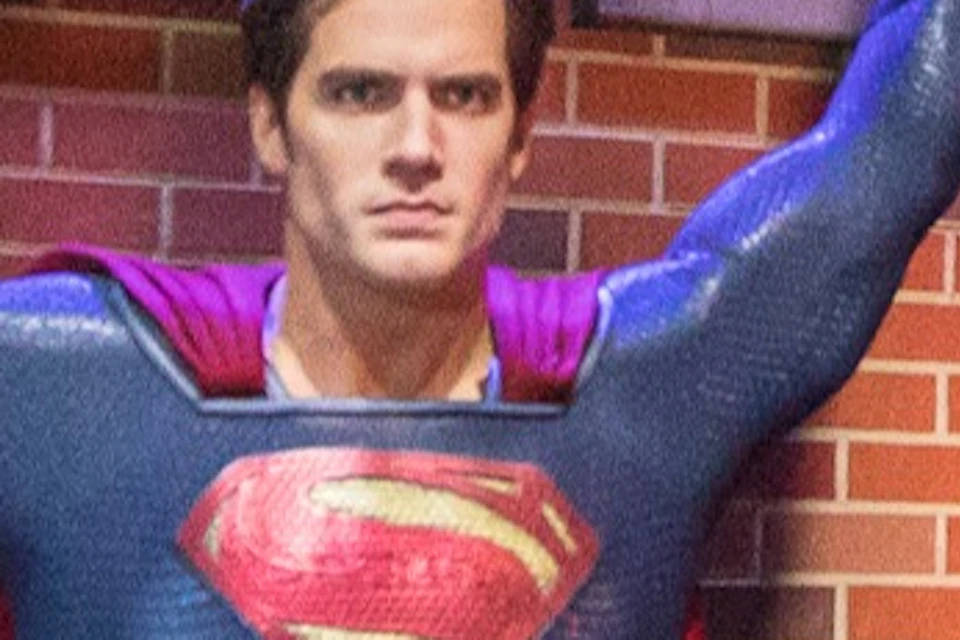 People posing next to a Superman statue holding up a helicopter in a brightly lit exhibit setting.