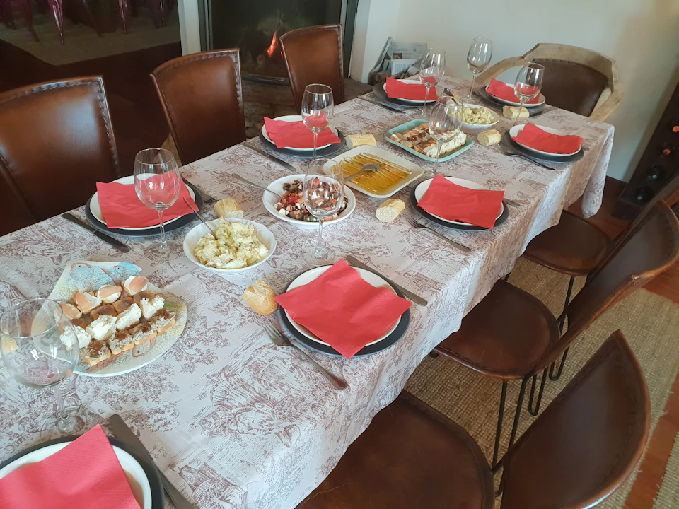 A dining table set with plates, red napkins, wine glasses, and various appetizers, with a fireplace in the background.