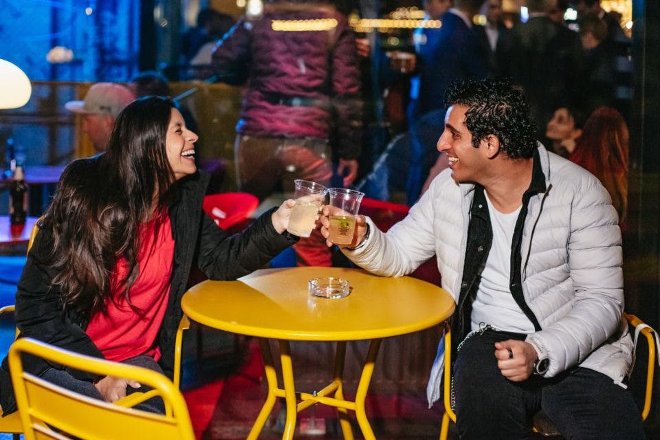 Smějící se žena a usmívající se muž cinkající poháry v klubu