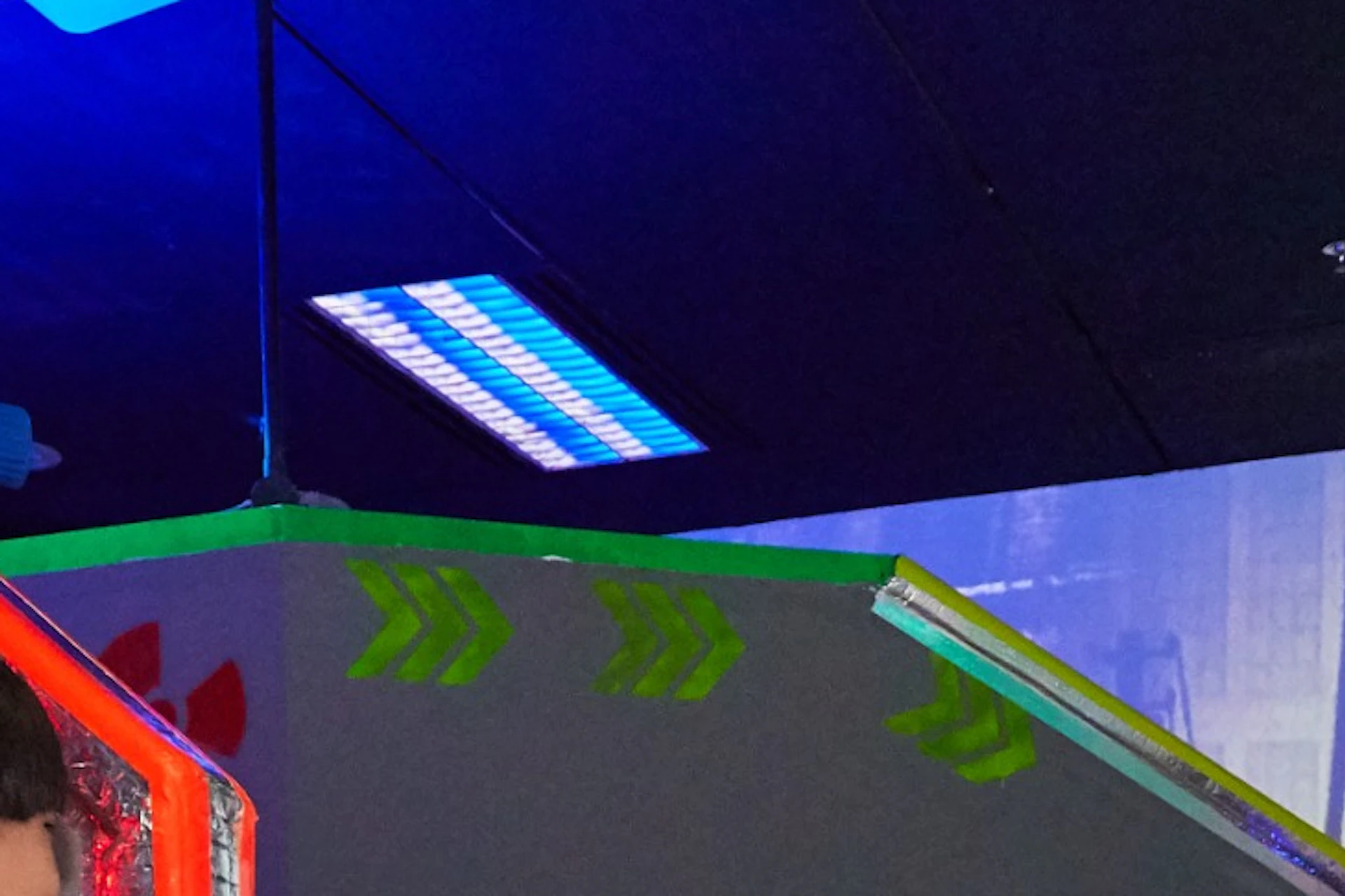 People playing laser tag in an indoor arena, wearing vests and holding laser guns, with colorful lighting effects.
