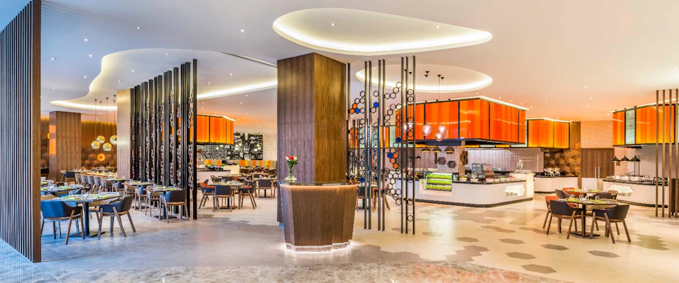 Modern restaurant interior with vibrant orange accents, decorative panels, wooden elements, and stylish seating arrangements.