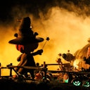 A pumpkin-headed figure dressed as a wizard stands in a smoky, eerie scene surrounded by jack-o'-lanterns and a large pumpkin.