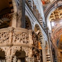 Four people stand smiling in a cathedral with ornate arches, pillars, and a decorated ceiling in the background.