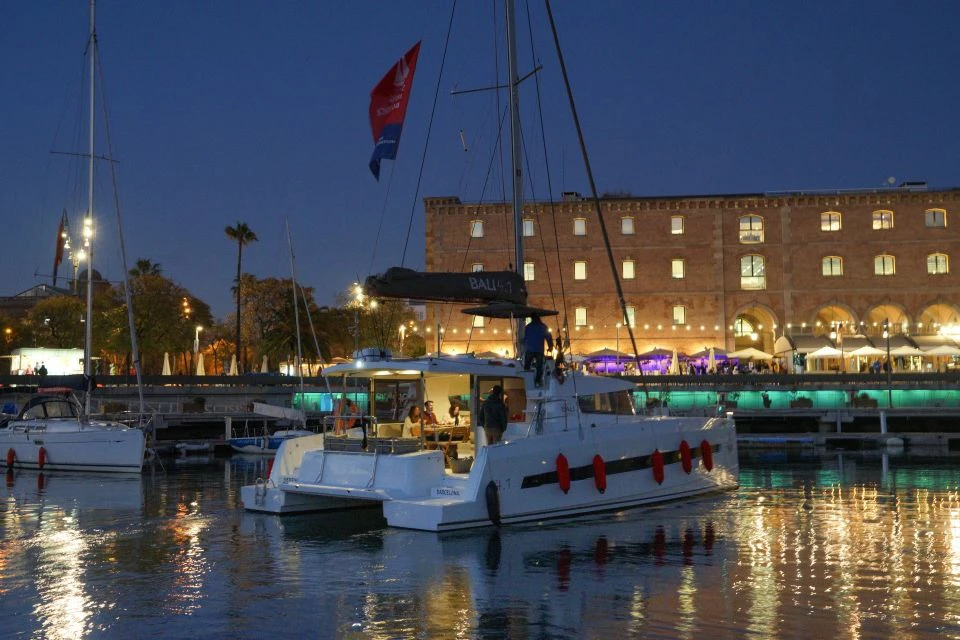 The catamaran on the water at night, with people on board enjoying their meal.