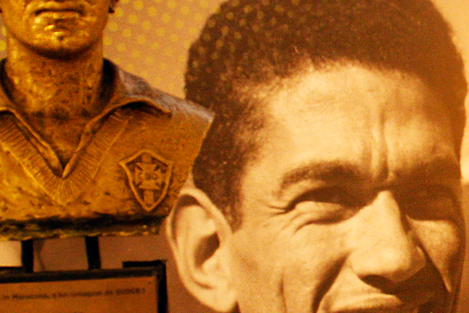 Bust and large photo of soccer player Garrincha, with his name displayed in bold on a wall behind the exhibit.