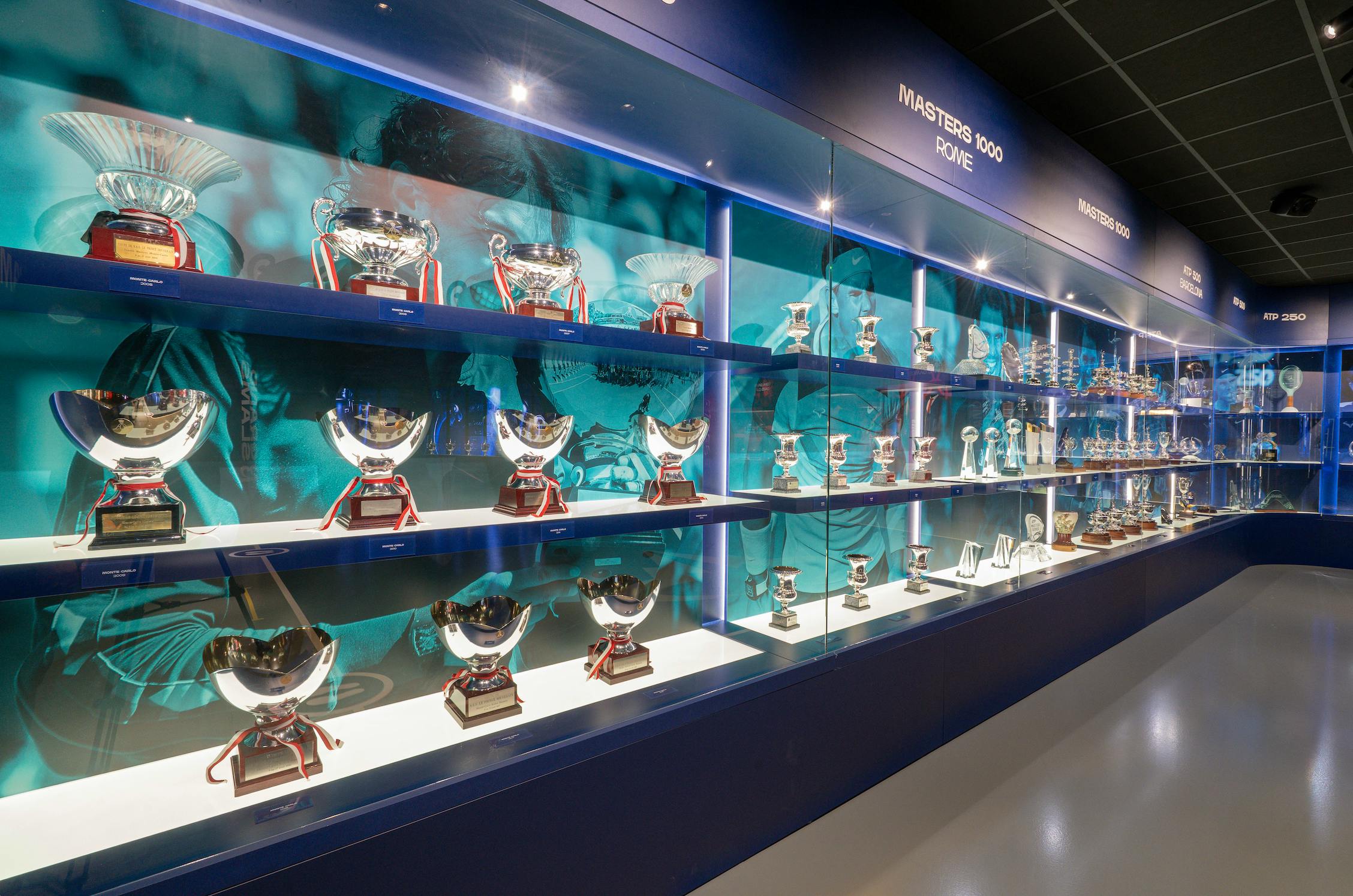 Vitrina con numerosos trofeos y premios, con fondo azul y el texto "Masters 1000 Roma".