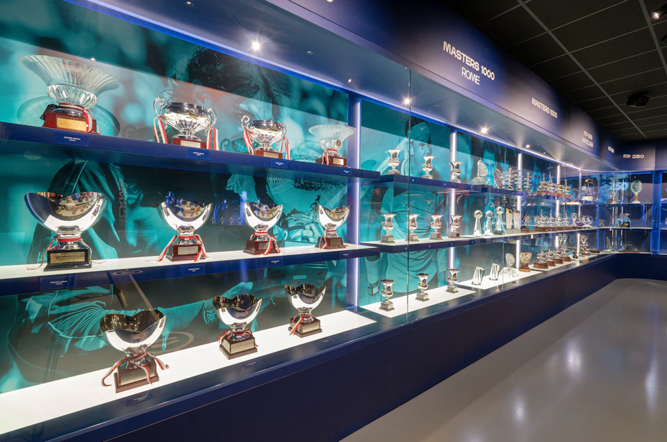 A display case featuring numerous trophies and awards, with a blue backdrop and the text 'Masters 1000 Rome.'