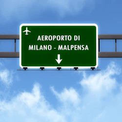 Grön vägskylt för "Aeroporto di Milano - Malpensa" med en flygplansikon, mot en blå himmel med moln.
