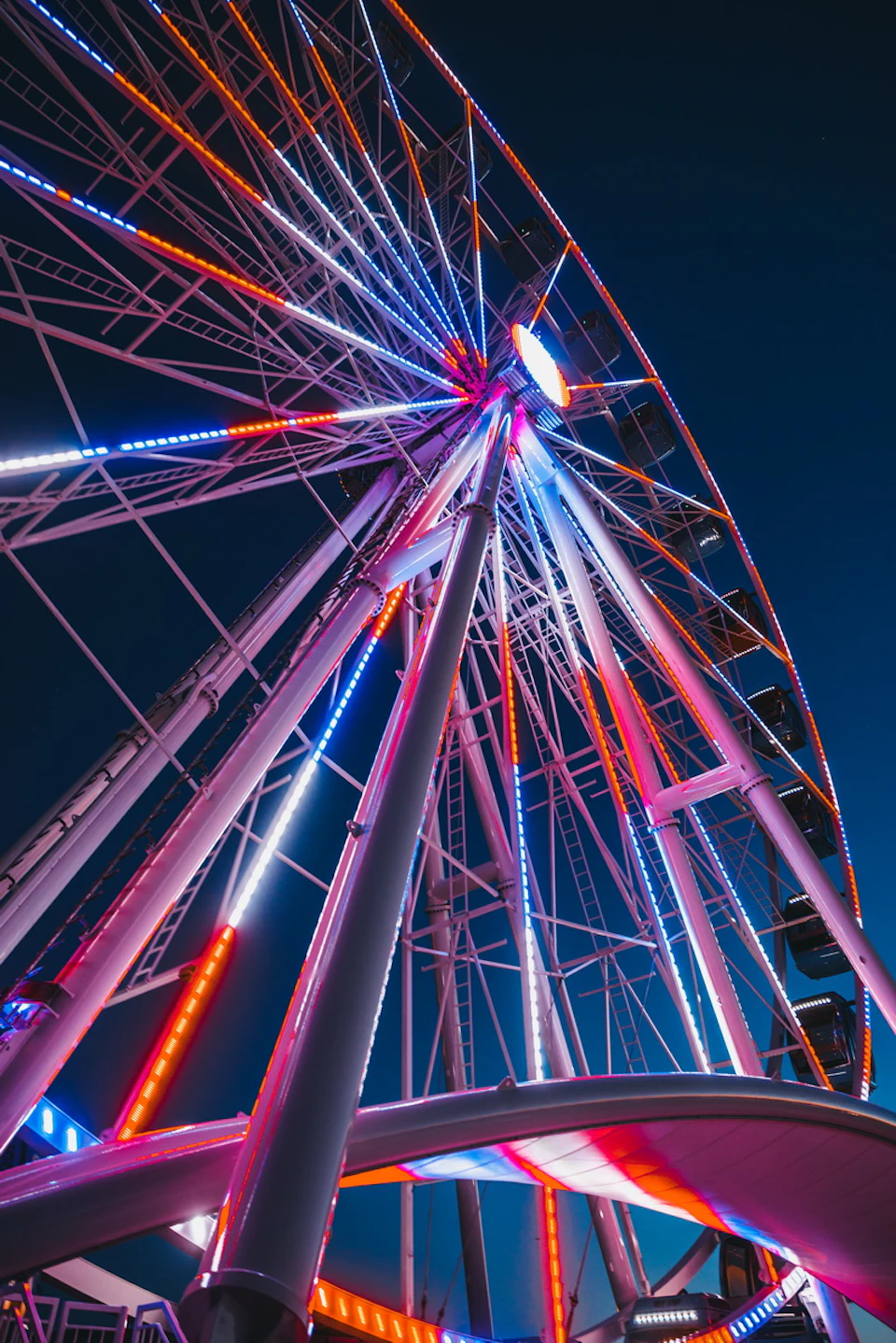 A Ferris wheel illuminated with colorful lights against a dark evening sky.