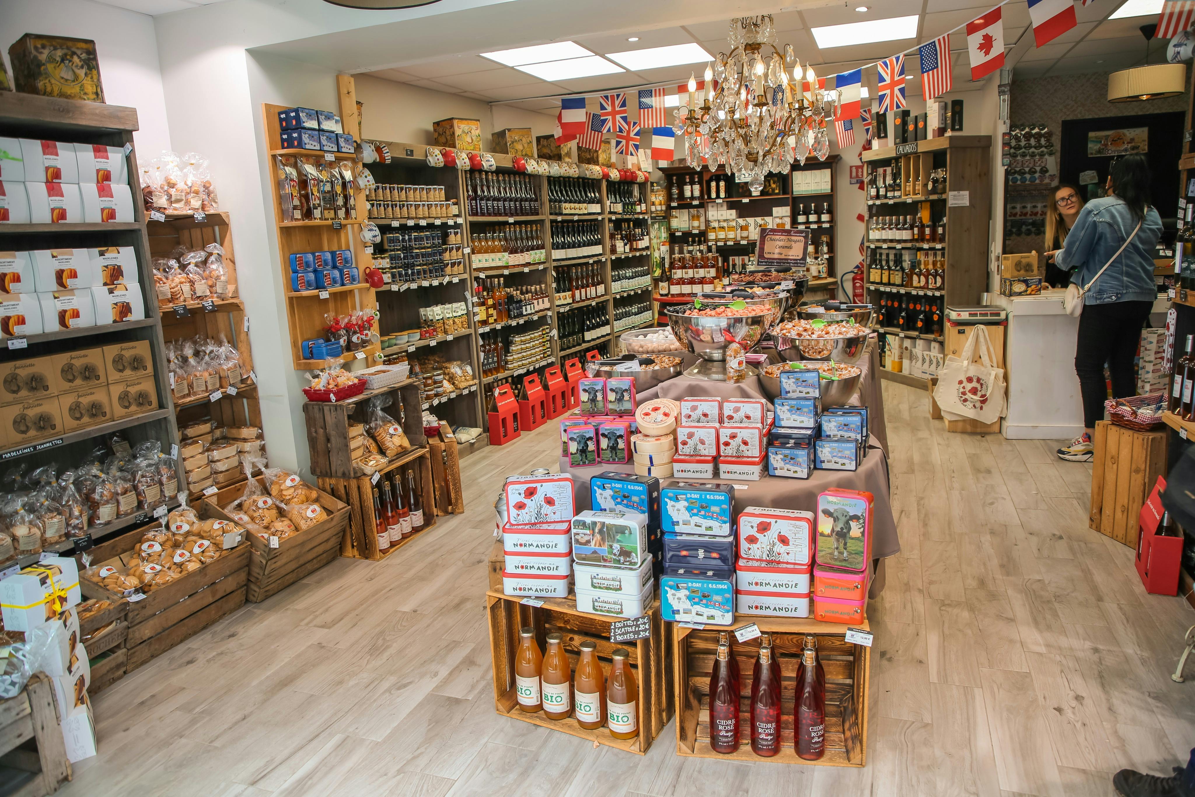 Ένα έντονα φωτισμένο εξειδικευμένο κατάστημα τροφίμων με ράφια διαφόρων ειδών, ένα κεντρικό τραπέζι με καραμέλες και διεθνείς σημαίες που κρέμονται από πάνω.