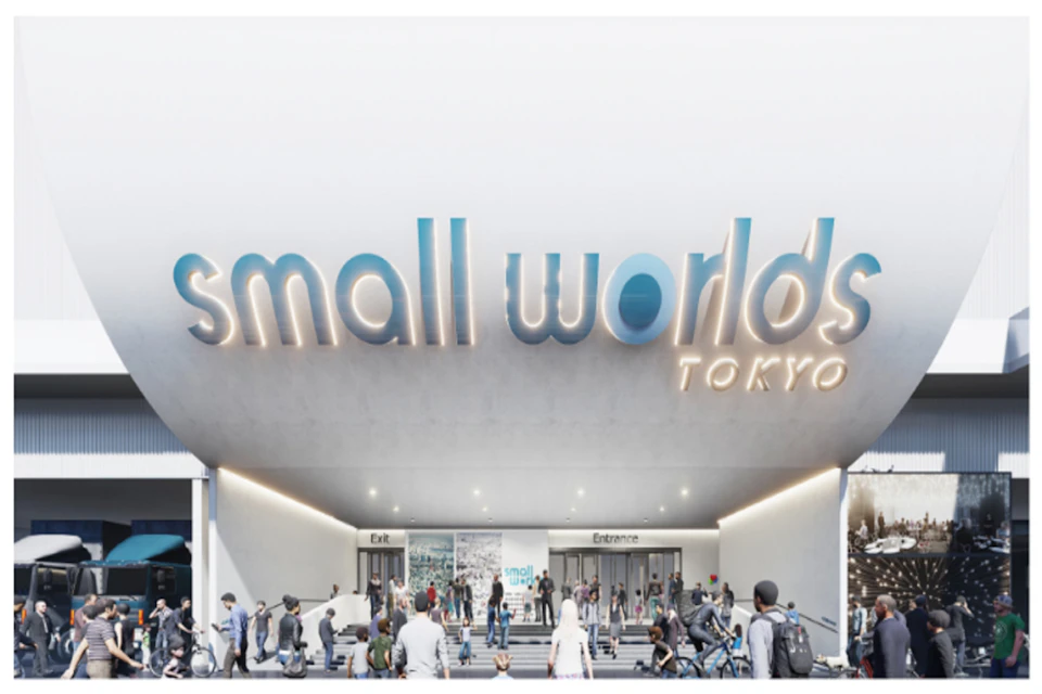 Crowd of people outside the entrance to Small Worlds Tokyo, illuminated sign overhead, with "Exit" and "Entrance" doors visible.