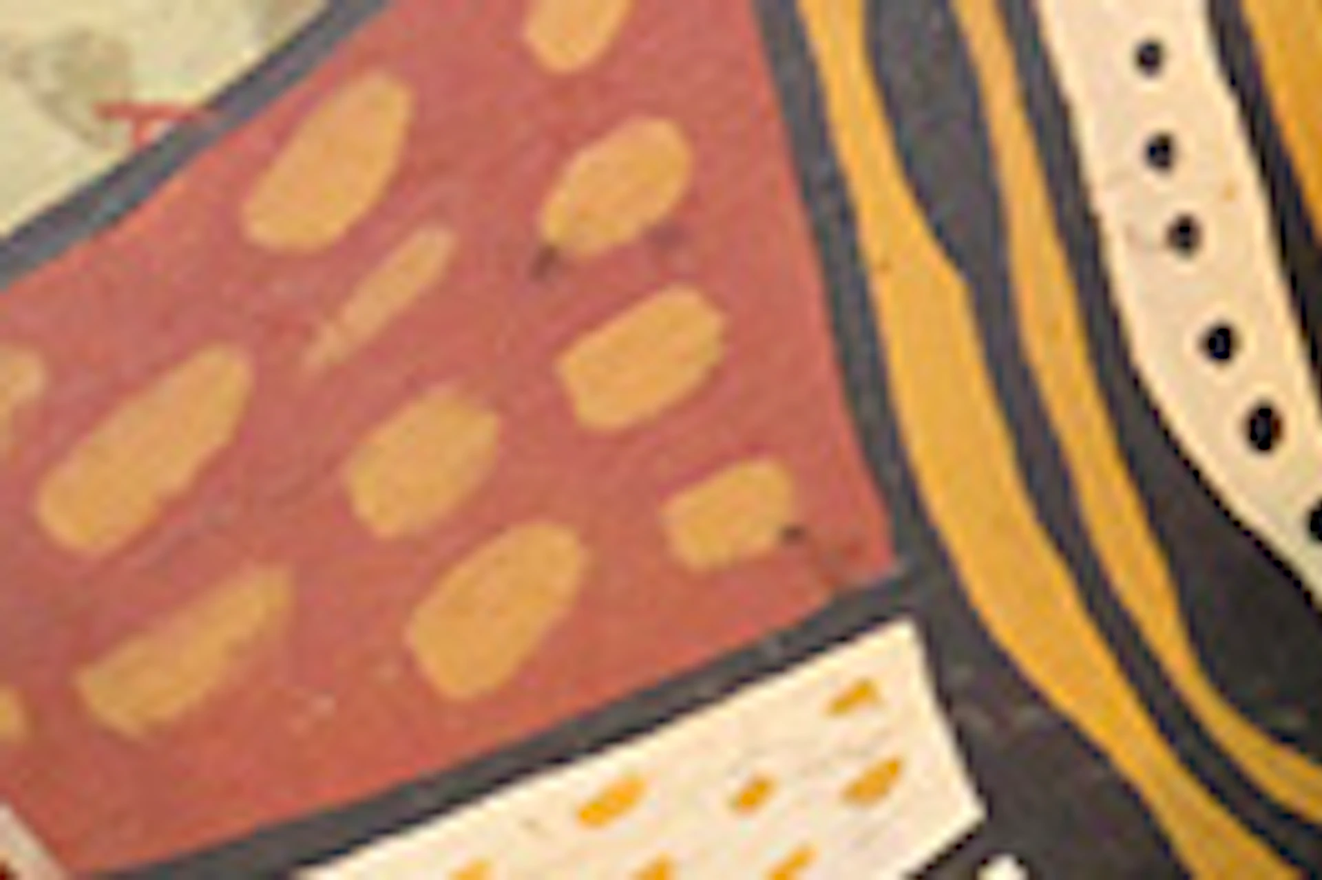 Two people kneel in front of colorful Aboriginal art. One is playing a didgeridoo while the other holds a similar instrument.
