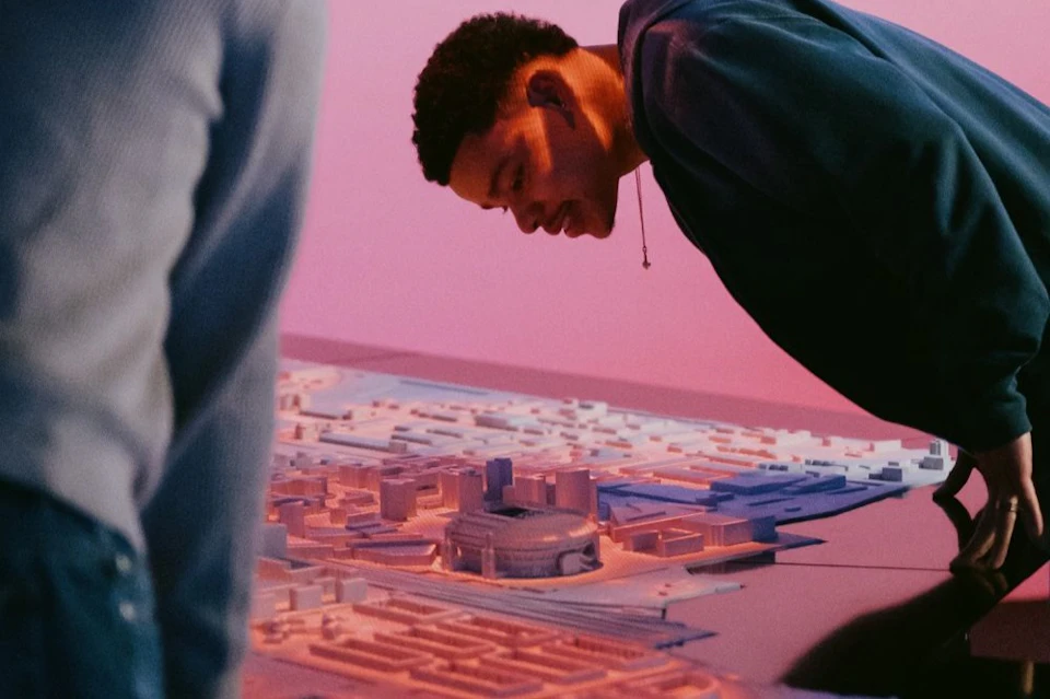 A person is examining a scaled architectural model of a city, illuminated by colourful lights.