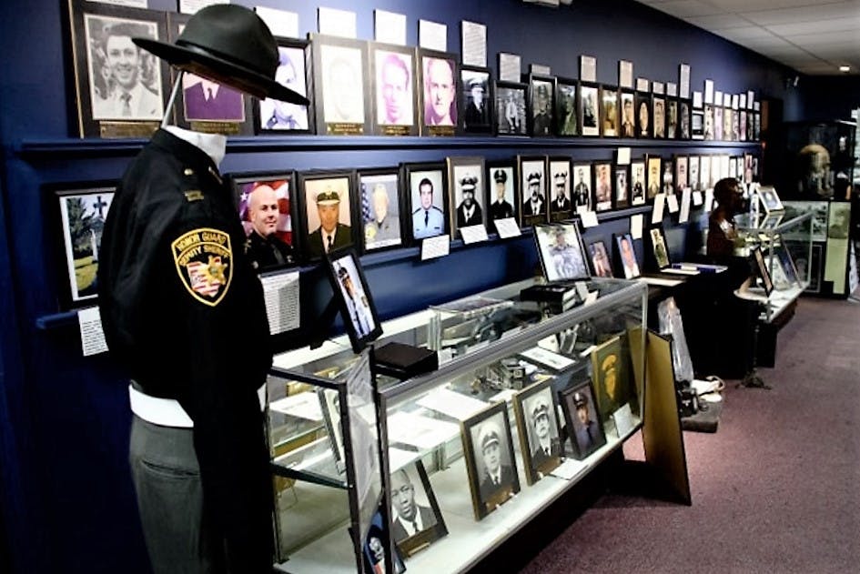 Expozice muzea s policejními a vojenskými fotografiemi, figurínou v uniformě a skleněnými vitrínami plnými memorabilií.