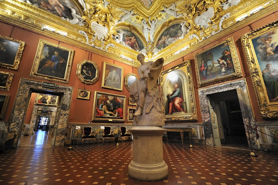 Ornate gallery room with classical paintings, a detailed marble statue in the center, gilded ceilings, and a checkered floor.