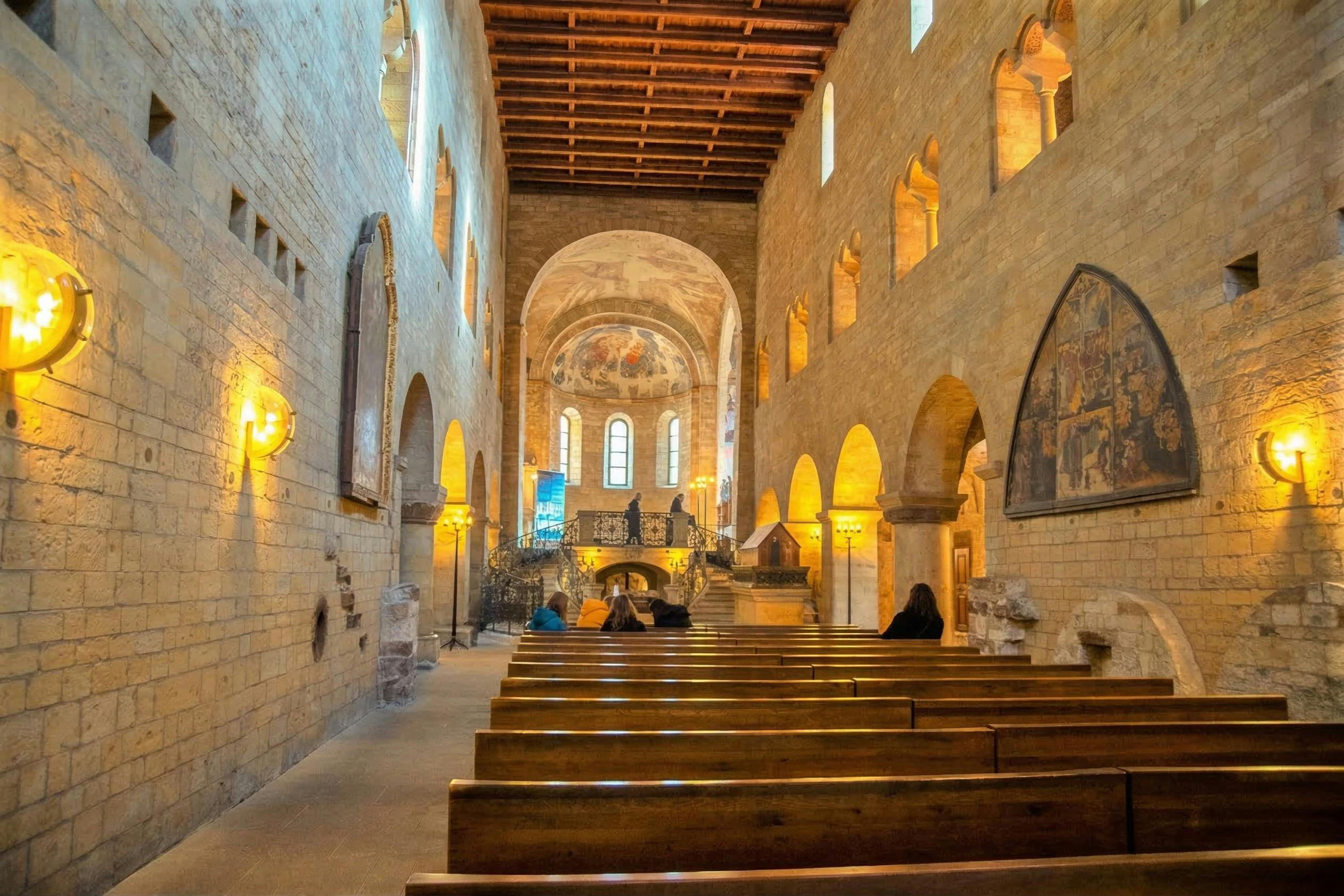 Εσωτερικό ιστορικής εκκλησίας με ξύλινα στασίδια, τοξωτά παράθυρα και ζωγραφισμένη οροφή με τρούλο. Οι άνθρωποι κάθονται στα στασίδια.