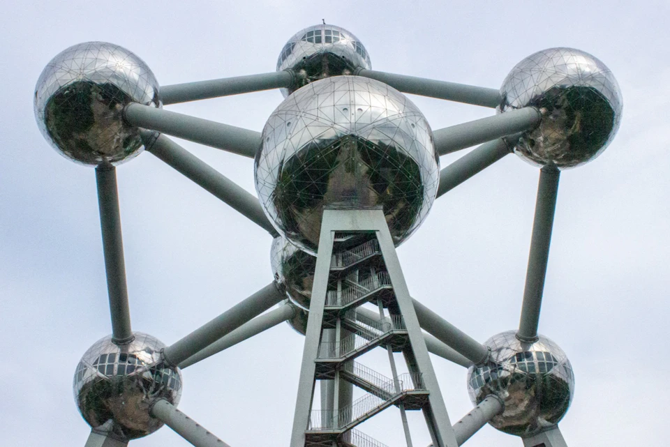 A close-up view of the Atomium structure with reflective spheres and connecting beams under a cloudy sky.