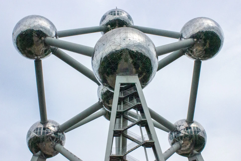A close-up view of the Atomium structure with reflective spheres and connecting beams under a cloudy sky.