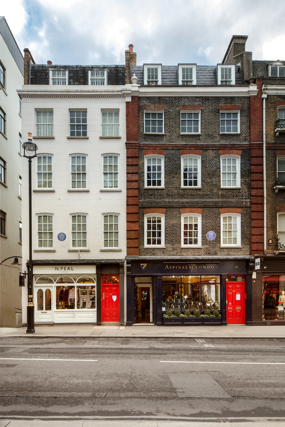 Street view of two adjacent multi-story buildings with storefronts: N.Peal, selling clothing, and Aspinal of London, selling accessories.