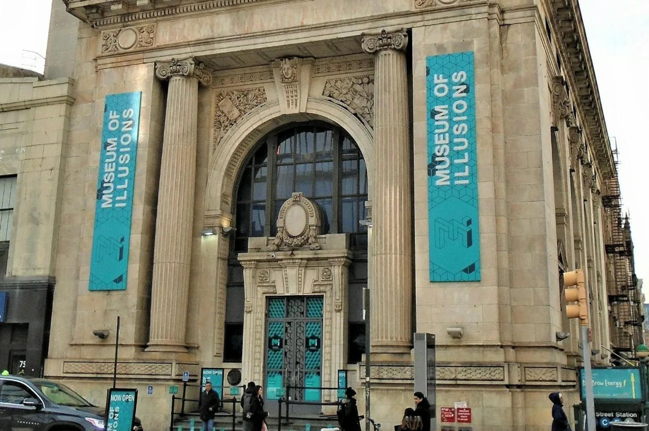 Facade of the Museum of Illusions building featuring ornate architecture and large banners with the museum's name.