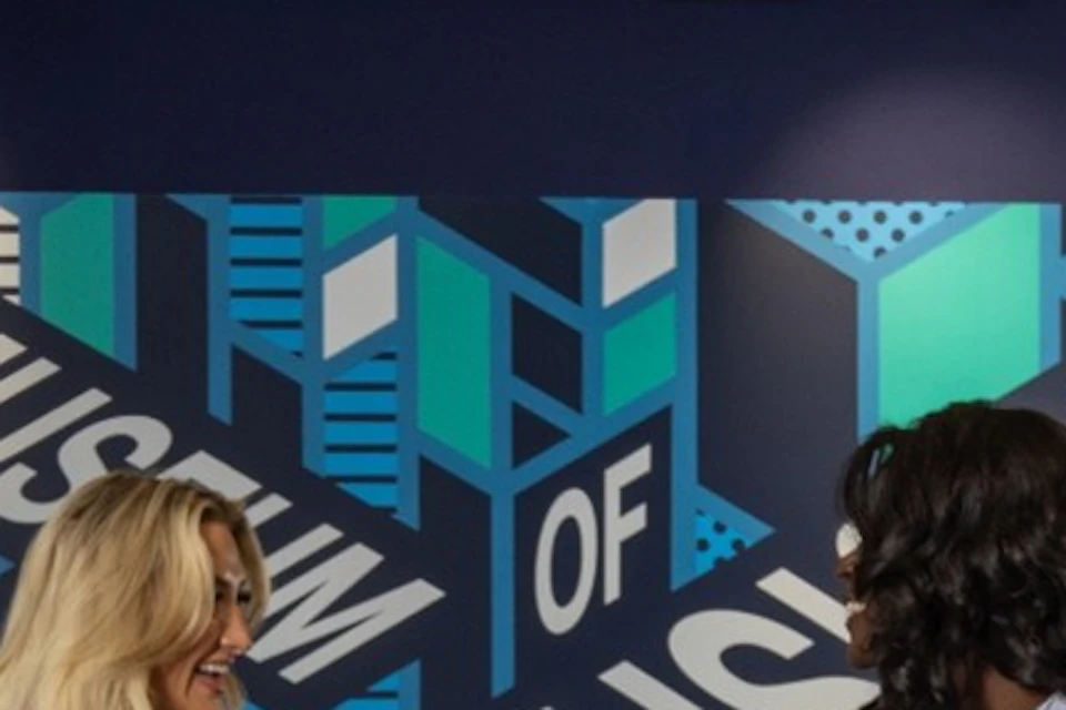 People interacting with exhibits at a Museum of Illusions, featuring colorful displays and interactive puzzles.