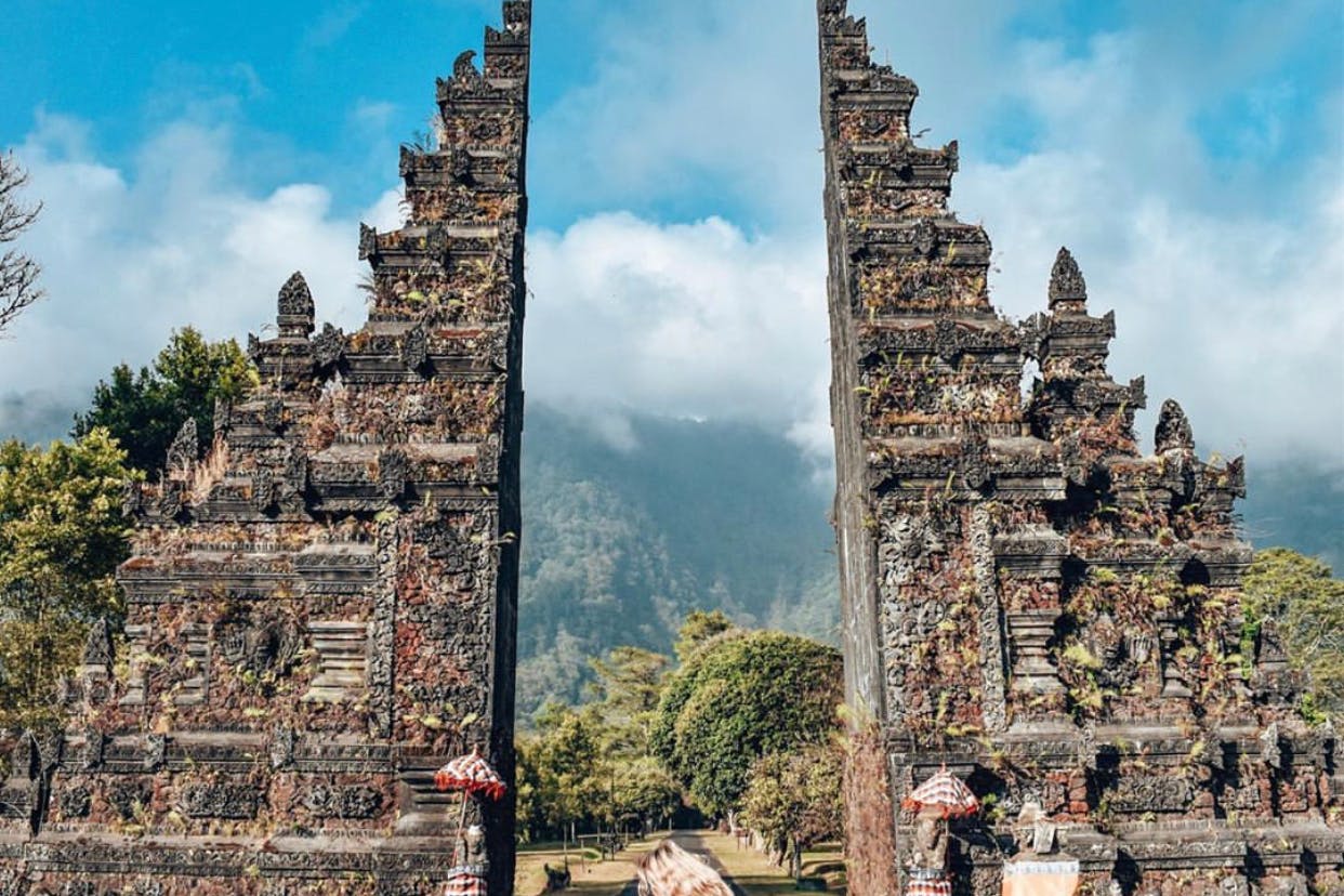 울창한 산과 구름을 배경으로 정교하게 조각된 석문이 빨간색과 흰색 우산과 나란히 놓여 있습니다.